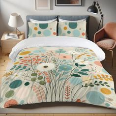 a bed with a white comforter covered in colorful flowers and circles on it's cover