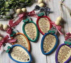 four wooden ornaments with words on them and bows hanging from the strings next to some greenery