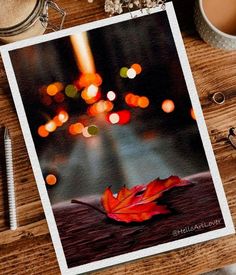 an autumn leaf on a wooden table next to a cup of coffee and some other items