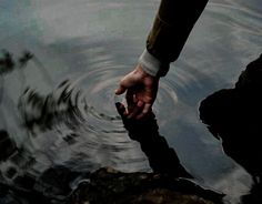 a person's hand reaching for something in the water