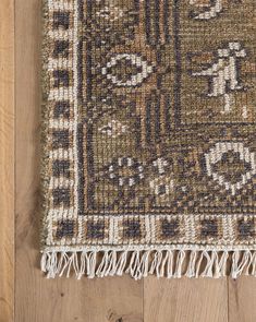 a brown and white rug with fringes on top of a wooden floor next to a wall