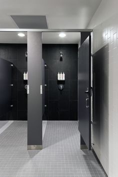 an empty bathroom with black and white tile on the walls, two urinals in the middle