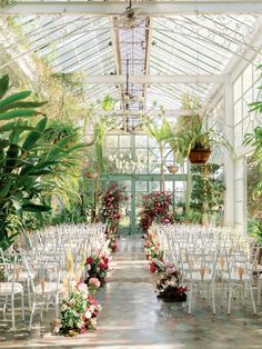 the inside of a greenhouse with rows of chairs and flowers on either side of the aisle