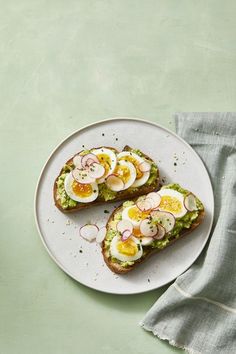 two pieces of toast with eggs and radishes on them sitting on a plate