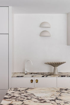 a kitchen with marble counter tops and white cabinets in the back ground, along with an island