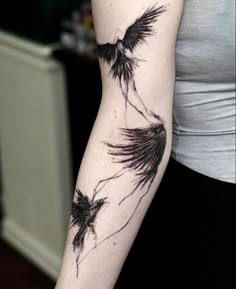 a woman's arm with two black birds flying in the sky on her left arm