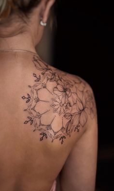 the back of a woman's shoulder with flowers and leaves tattooed on her arm