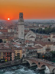 the sun is setting over an old city with bridges and buildings on either side of it