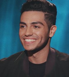 a close up of a person with a smile on his face and wearing a black shirt