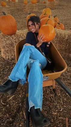 a woman sitting in a chair with pumpkins on the ground