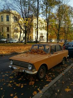 an old car is parked on the side of the road with leaves all over it