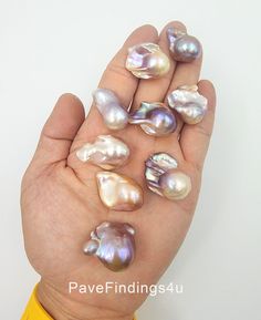 a hand holding several different types of pearls