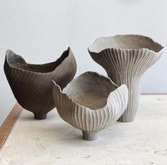 three vases sitting on top of a table next to each other in front of a white wall