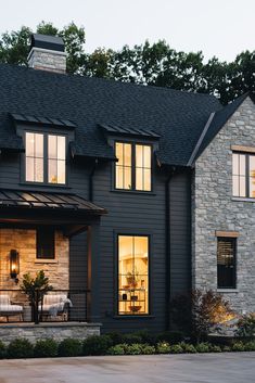 a house that has some lights on in front of it and the windows are lit up