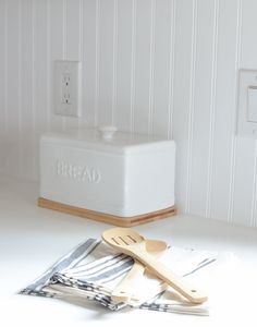 wooden utensils are sitting on the counter next to a bread box