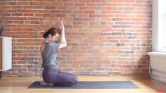 a woman is doing yoga in front of a brick wall