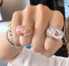 a woman is pointing at the camera with two rings on her finger and another ring in front of her