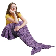 a woman sitting on the ground with a purple mermaid tail blanket over her head and hand under her chin