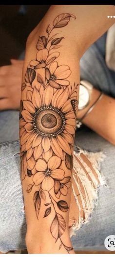 a sunflower tattoo with an eye on it's arm and flowers around the leg