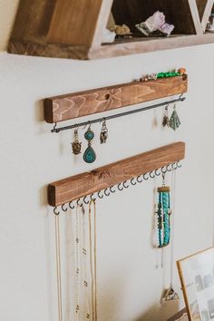 a wooden shelf with jewelry hanging from it's sides next to a framed photograph