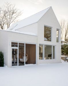 a white house in the snow with large windows