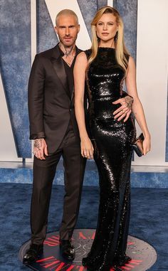 man and woman in formal wear standing on blue carpet at red carpet with black dress