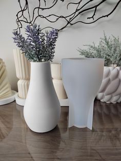 three white vases sitting on top of a wooden table