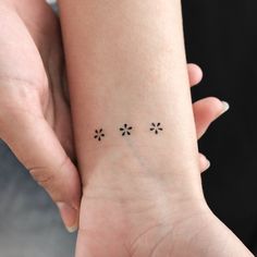 a woman's wrist with three small flowers on the left side of her arm