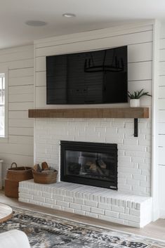 a living room with a fireplace and television mounted on the wall above it's mantle