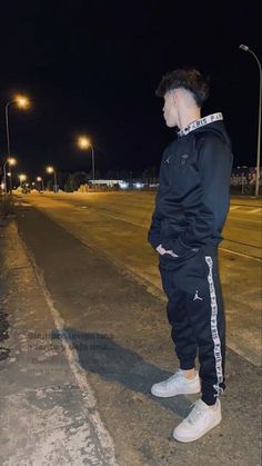 a man standing in the middle of an empty street at night with his hands on his hips