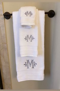 two white towels hanging on a towel rack in a bathroom with the word mr and mrs written on them