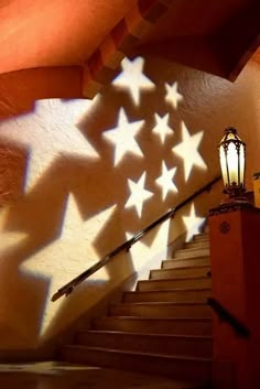 the shadows of stars cast on stairs in front of a wall with a light fixture