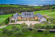 an aerial view of a house in the middle of a lush green field with trees