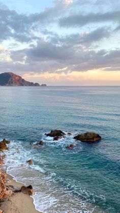 an ocean view with waves crashing on the shore and rocks in the water at sunset