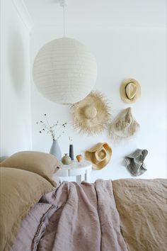 a bed room with a neatly made bed and two hats on the wall above it