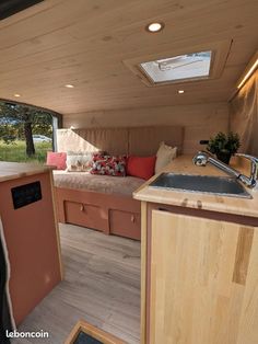 the kitchen and living area of an rv with wood paneling on the walls, windows, and sink