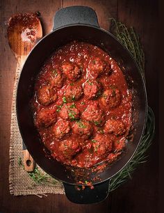 meatballs in marinara sauce and bread on a wooden table next to a spoon