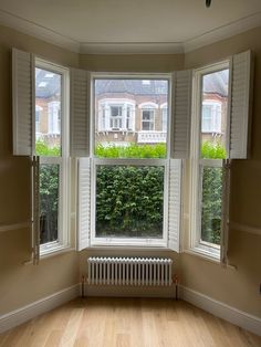 an empty room with three windows and a radiator