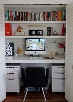 a desk with a computer on top of it in front of a bookshelf