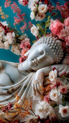 a white buddha statue surrounded by pink and white flowers