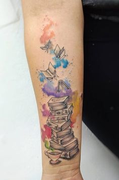 a person with a tattoo on their arm has a stack of books in the air