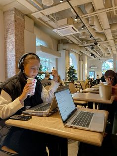 a person sitting at a table with a laptop and headphones in front of them