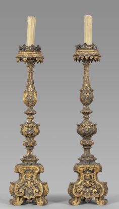 two gold candlesticks sitting next to each other