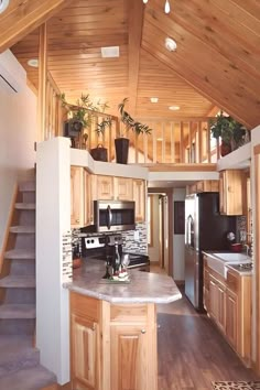 a kitchen with wooden walls and stairs leading up to the second floor, along with an island