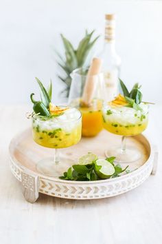 three glasses filled with food sitting on top of a white plate next to pineapples