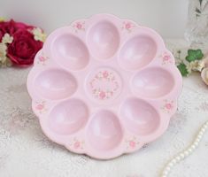 a pink plate sitting on top of a table next to some flowers and bead