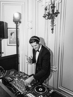 a man in a tuxedo mixing music on a turntable with headphones