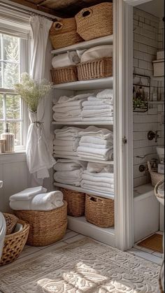 a bathroom with lots of white towels and baskets on the shelves in front of it