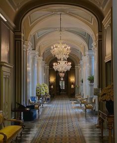 an ornate hallway with chandeliers and chairs in the center is lined with yellow flowers