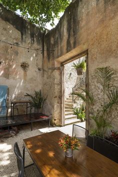 a wooden table sitting under a tree next to a stone building with an open door